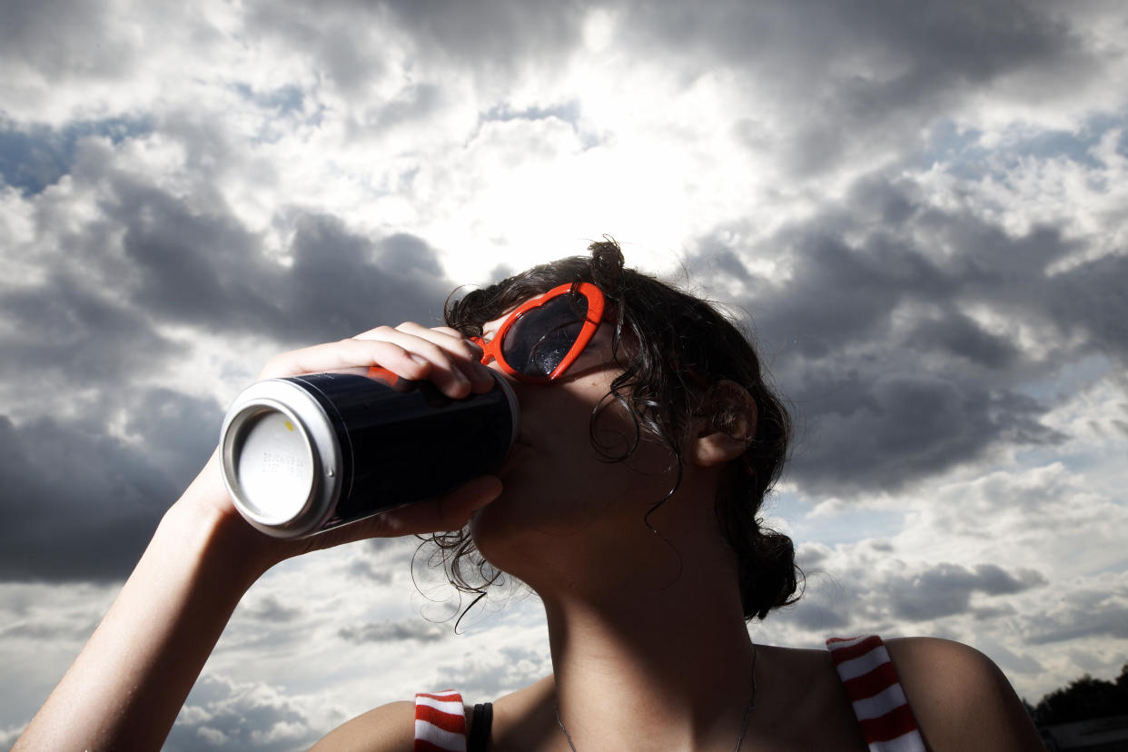 A girl drinks an energy drink.