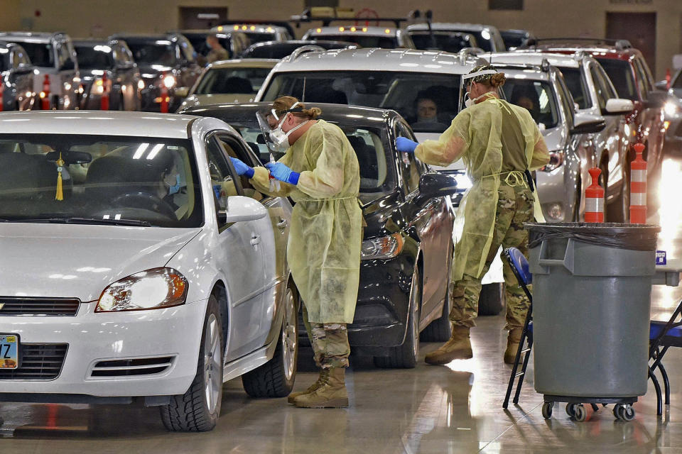 FILE - In this Nov. 17, 2020, file photo, North Dakota National Guard soldiers Spc. Samantha Crabbe, left, and Master Sgt. Melanie Vincent administer COVID-19 tests inside the Bismarck Events Center in Bismarck, N.D. As much of the country experiences spiking virus rates, a reprieve from a devastating surge of the coronavirus in the Upper Midwest has given cautious relief to health officials, though they worry that infections remain rampant and holiday gatherings could reignite the worst outbreaks of the pandemic. (Tom Stromme/The Bismarck Tribune via AP, File)