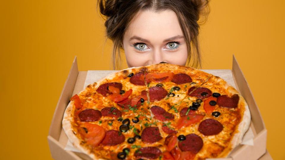 Lovely cute positive young woman hiding behind pizza