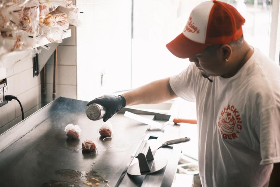 Burgers are seasoned with just salt and pepper and topped with thinly sliced onions, before being smashed on the grill. Stephen Yang