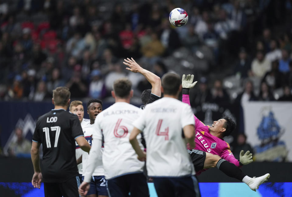 Vancouver Whitecaps goalkeeper Yohei Takaoka, back right, watches the ball after making a save against Minnesota United's Michael Boxall during the first half of an MLS soccer match in Vancouver, British Columbia, Saturday, May 6, 2023. (Darryl Dyck/The Canadian Press via AP)