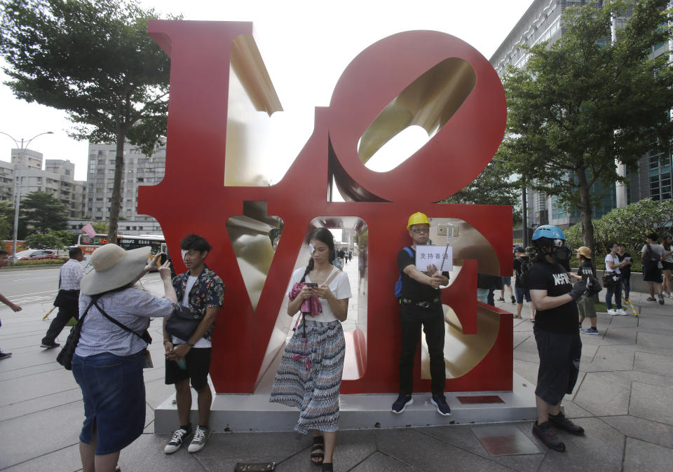 Participants of a rally with their eyes covered in red-eyepatch, symbolizing a women reported to have had an eye ruptured by a beanbag round fired by police during clashes, take selfies in Taipei, Taiwan, Saturday, Aug. 17, 2019. More than 100 people gathered to support Hong Kong's pro-democracy protesters. (AP Photo/Chiang Ying-ying)
