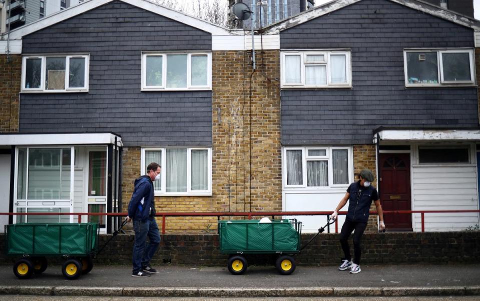 Volunteers cart food donations from a local food bank through the Carpenters Estate in Stratford in east London (REUTERS)