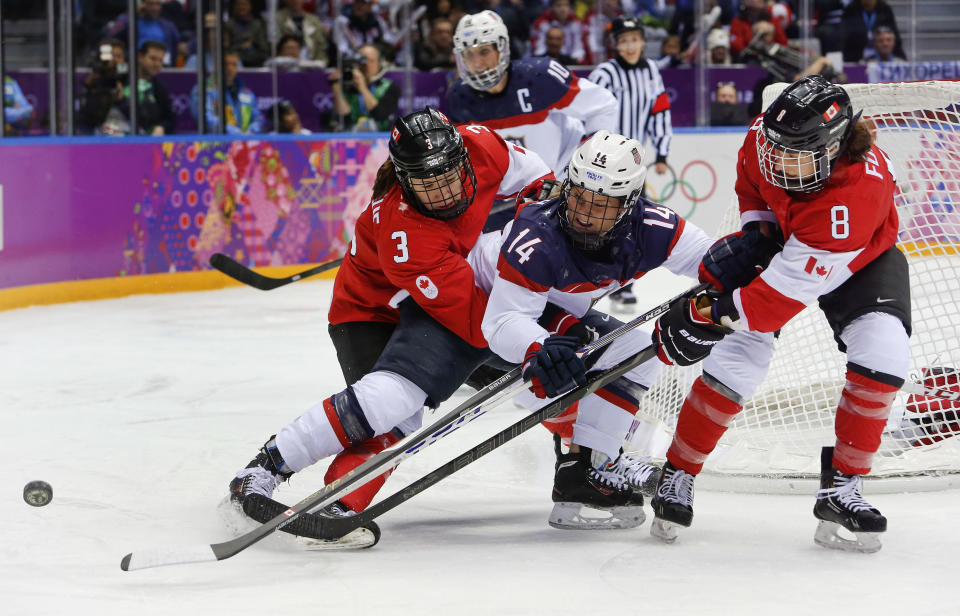 Brianna Decker of the United States (14) battles Jocelyne Larocque (3) and Laura Fortino of Canada (8) for the puck during the first period of the women's gold medal ice hockey game at the 2014 Winter Olympics, Thursday, Feb. 20, 2014, in Sochi, Russia. (AP Photo/Mark Humphrey)