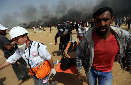 A wounded demonstrator is evacuated during clashes with Israeli troops at a protest where Palestinians demand the right to return to their homeland, at the Israel-Gaza border in the southern Gaza Strip, April 13, 2018. REUTERS/Ibraheem Abu Mustafa