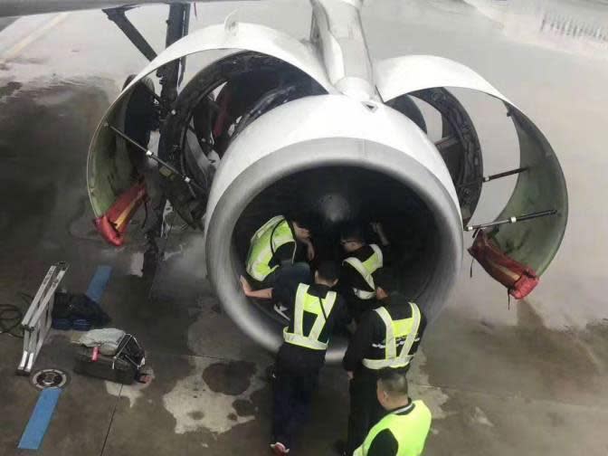 Officials examine the aircraft engine after an elderly woman threw in coins for good luck: Facebook/China People's Daily