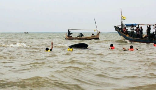 Tourist boats surround rescuers trying to free a sperm whale (C) stuck in shallow waters at Pakis Jaya beach in Karawang, West Java, July 27, 2012. Local residents were paying the equivalent of half a US dollar each for boat rides close to the whale. Some had jumped off the boats and onto the whale on Wednesday, causing wounds to its body