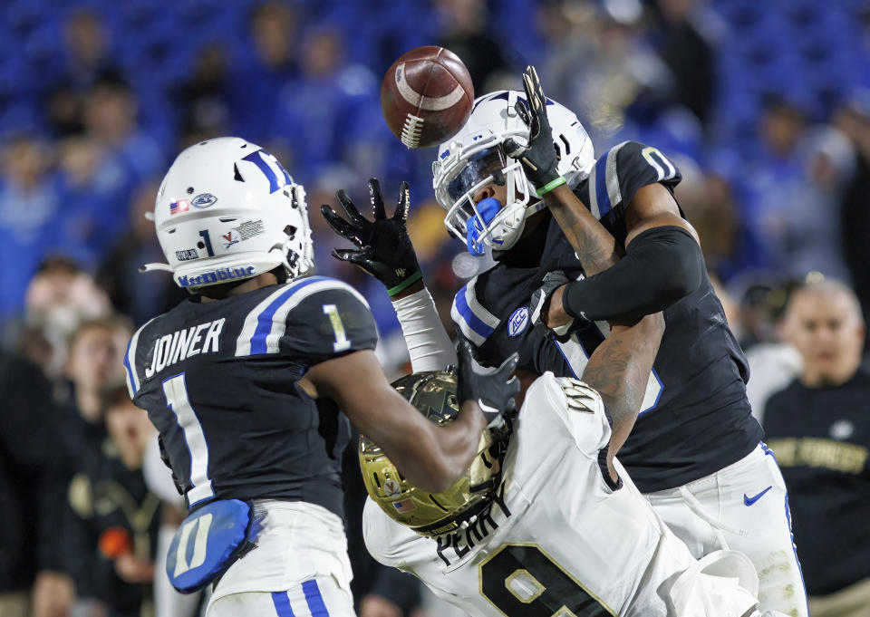 The football flies past Wake Forest's A.T. Perry and Duke's Chandler Rivers into the hands of Darius Joiner (1) for an interception late in the second half of an NCAA college football game in Durham, N.C., Saturday, Nov. 26, 2022. (AP Photo/Ben McKeown)