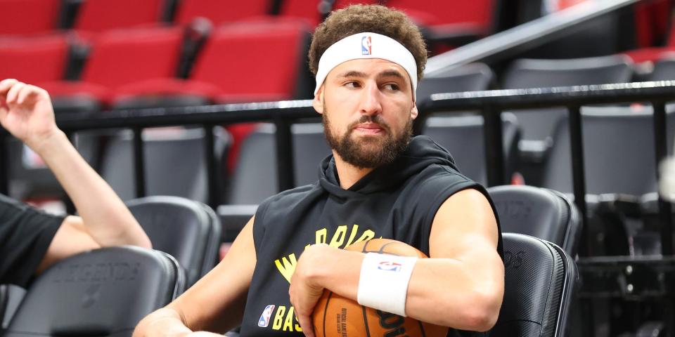 Klay Thompson sits in a chair and holds a basketball.