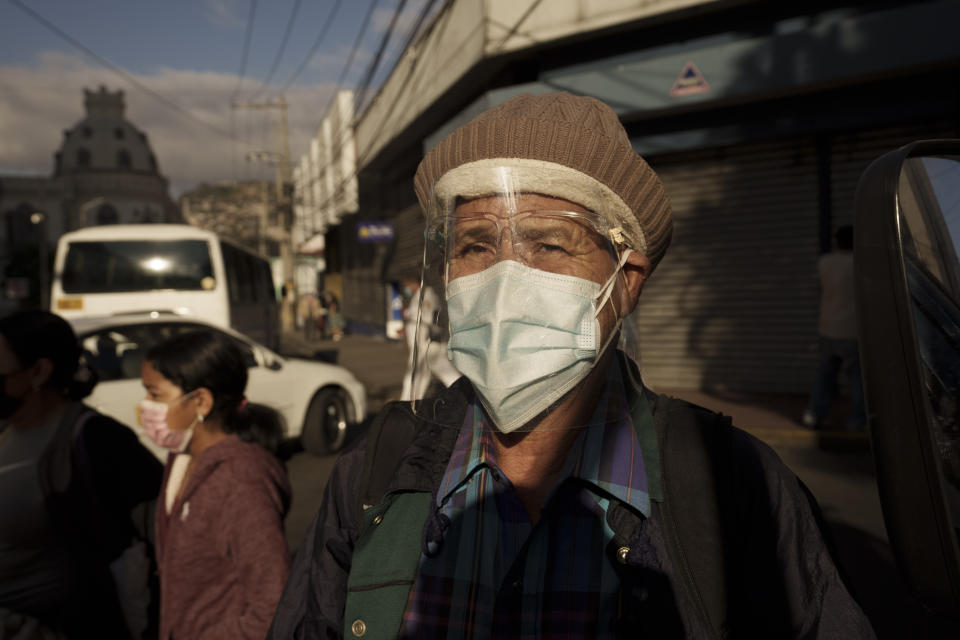 A man wearing protective face gear due to the COVID-19 pandemic walks past Congress being occupied by supporters loyal to President-elect Xiomara Castro in Tegucigalpa, Honduras, Wednesday, Jan. 26, 2022. The new president's supporters say they want to block opposition attempts to take over leadership of Congress, which could threaten her ability to govern after she is sworn in Jan. 27. (AP Photo/Moises Castillo)