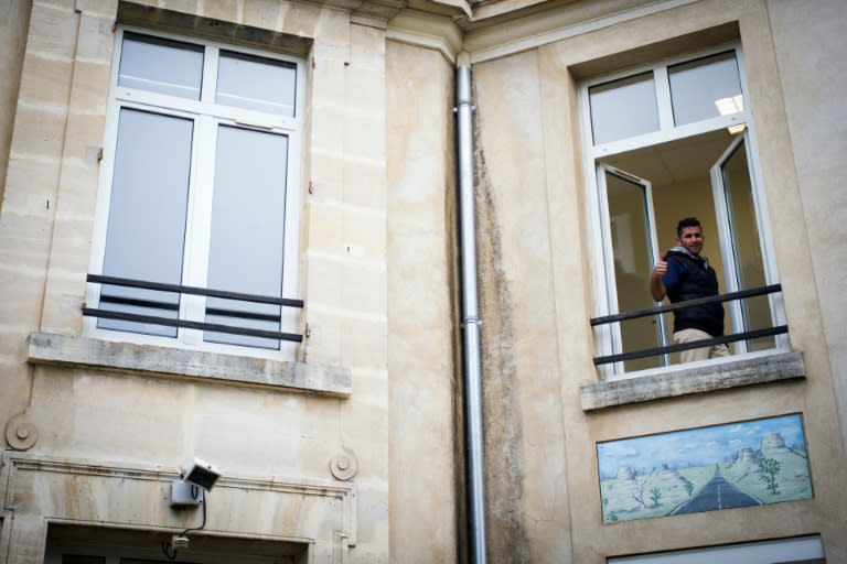 An Afghan migrant gestures at a refugee at a migrant camp in Forges-Les Bains, southeast of Paris, on October 24, 2016