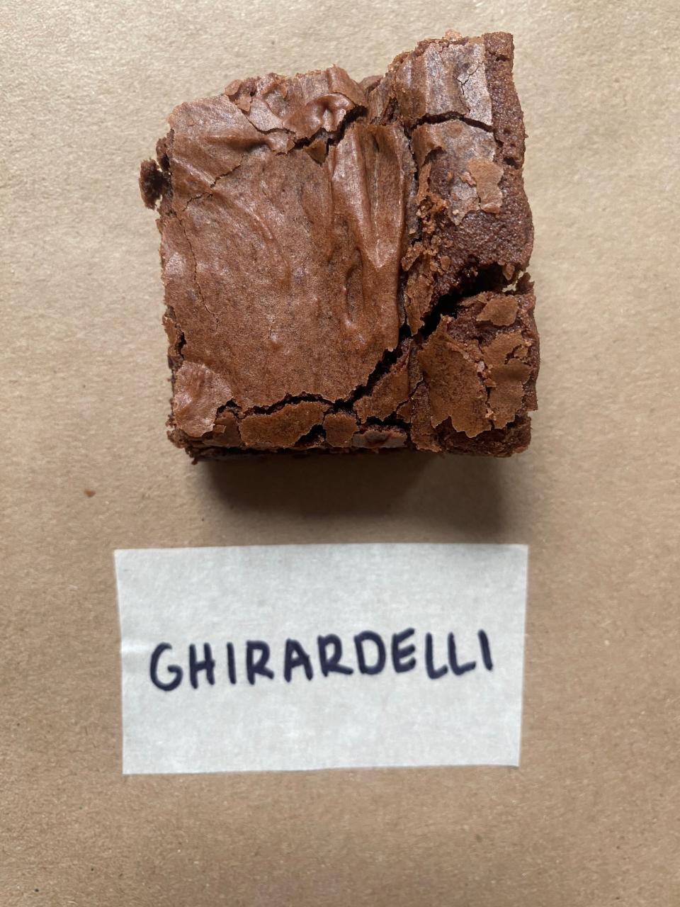 A Ghirardelli brownie with a cracked top is placed above the brand's name label
