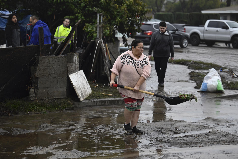 A woman removes debris from floods during a rain storm Monday, Jan. 22, 2024, in San Diego. (AP Photo/Denis Poroy)