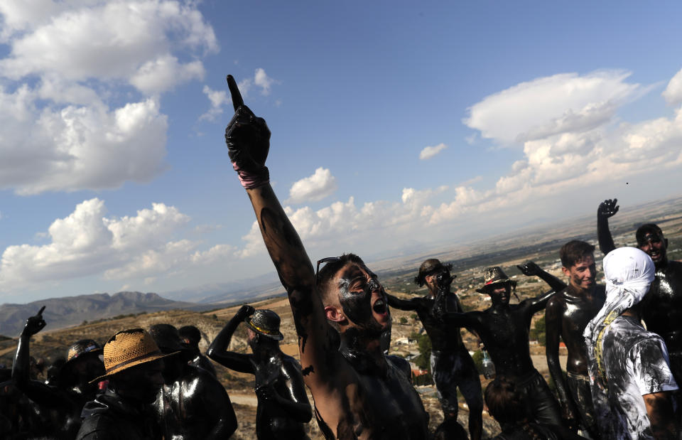 In this photo taken on Friday, Sept. 6, 2019, boys painted with black grease celebrate during the traditional festivities of the Cascamorras festival in Baza, Spain. During the Cascamorras Festival, and according to an ancient tradition, participants throw black paint over each other for several hours every September 6 in the small town of Baza, in the southern province of Granada. The "Cascamorras" represents a thief who attempted to steal a religious image from a local church. People try to stop him, chasing him and throwing black paint as they run through the streets. (AP Photo/Manu Fernandez)