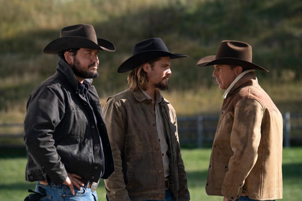 Three men in jackets and cowboy hats stand outside