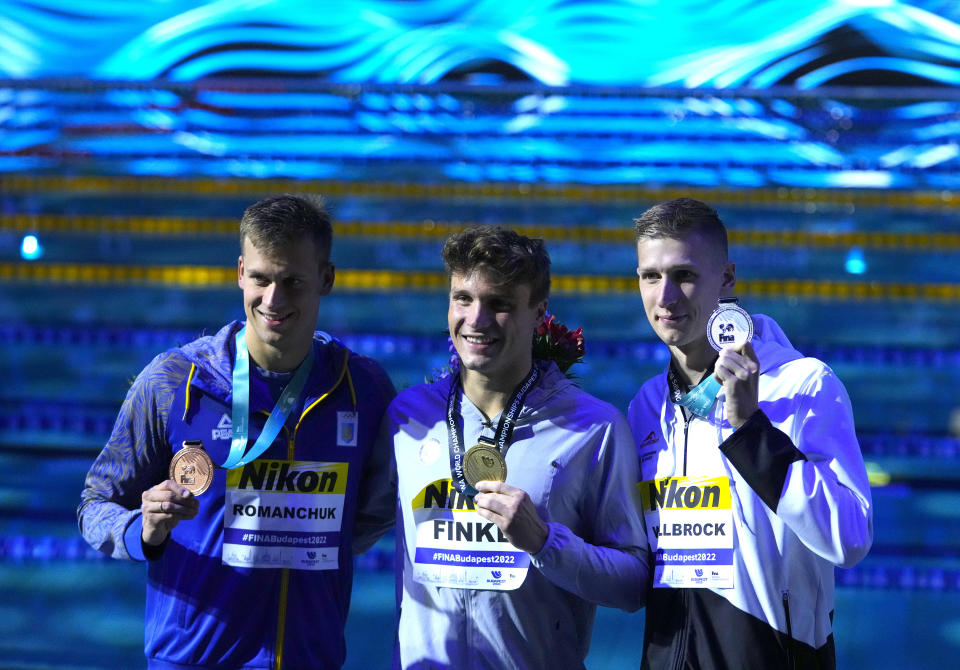 Mykhailo Romanchuk of Ukraine, Bobby Finke of the United States, Florian Wellbrock of Germany, from left to right, pose with their medals after the Men 800m Freestyle final at the 19th FINA World Championships in Budapest, Hungary, Tuesday, June 21, 2022. (AP Photo/Petr David Josek)