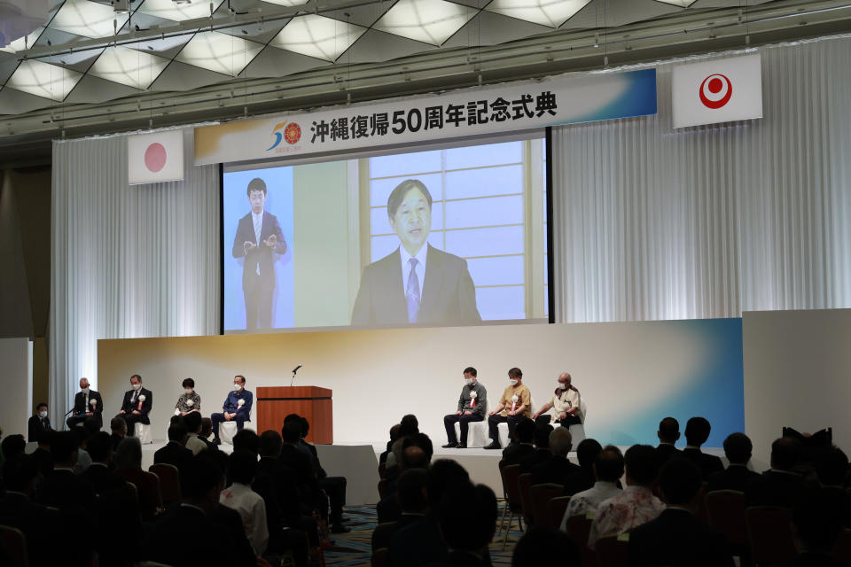 Japan's Emperor Naruhito, right on a screen, delivers a speech during a ceremony to mark the 50th anniversary of its return to Japan after 27 years of American rule, in Tokyo Sunday, May 15, 2022. The ceremonies are held in Tokyo and Okinawa simultaneously. (Rodrigo Reyes Marin/Pool Photo via AP)