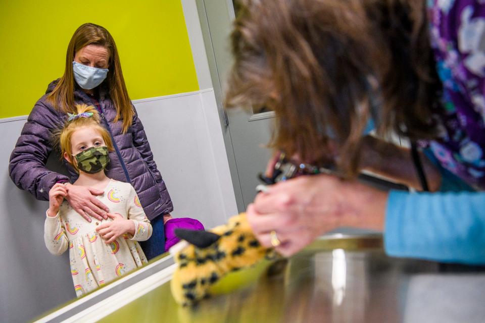 Colleen Seal, a registered veterinary technician, checks out Spot the cheetah during intake at the Stuffy Repair Clinic Tuesday as Ellie Buchanan watches and her mom, Melissa Buchanan, keeps an eye on her. Appointments at the clinic cost $20.