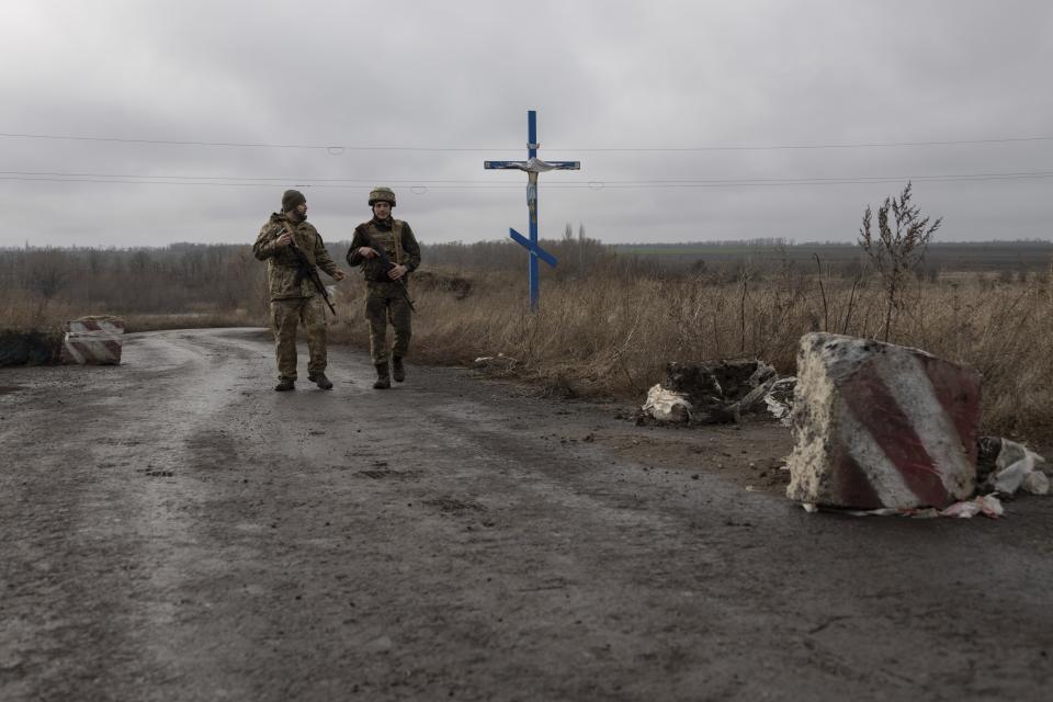 Ukrainian soldiers walk at the line of separation from Russia-backed rebels near the village of Nevelske in eastern Ukraine, on Friday, Dec. 10, 2021. The 7-year-old conflict has all but emptied the village, and a Russian troop buildup has stoked fears of renewed large-scale fighting, rattling already-nervous residents. (AP Photo/Andriy Dubchak)