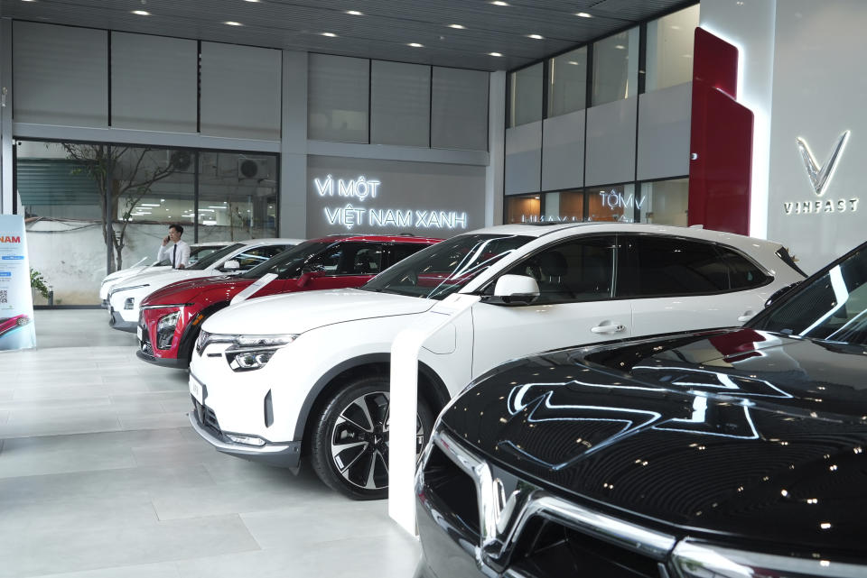 A salesman talks on phone next to Vinfast electric cars displayed in a showroom in Hanoi, Vietnam on June 10, 2024. Vietnamese automaker VinFast just can’t sell enough cars, so it's hoping its tiniest and cheapest car yet — a roughly 10-foot-long mini-SUV priced at $9,200 and called the VF3 — will become Vietnam's “national car" and win over consumers in Asian markets. (AP Photo/Hau Dinh)