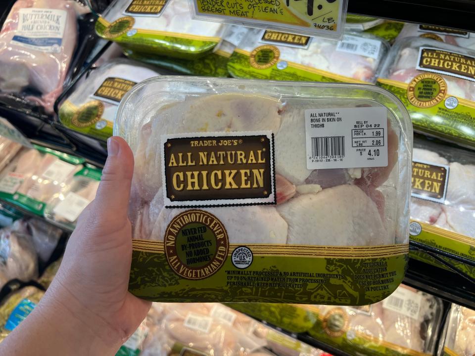 The writer holds a package of chicken thighs at Trader Joe's