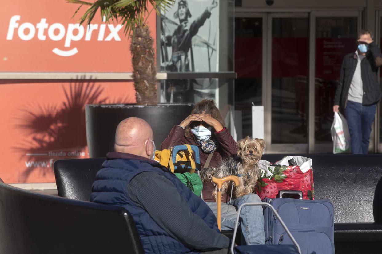 A woman wearing a face mask to protect against the spread of coronavirus sits outside a shopping center with a dog in Madrid, Spain on Thursday, Oct. 15, 2020. Spain has become the first European Union nation to reach 900,000 infections after adding more than 11,000 more confirmed COVID-19 cases.