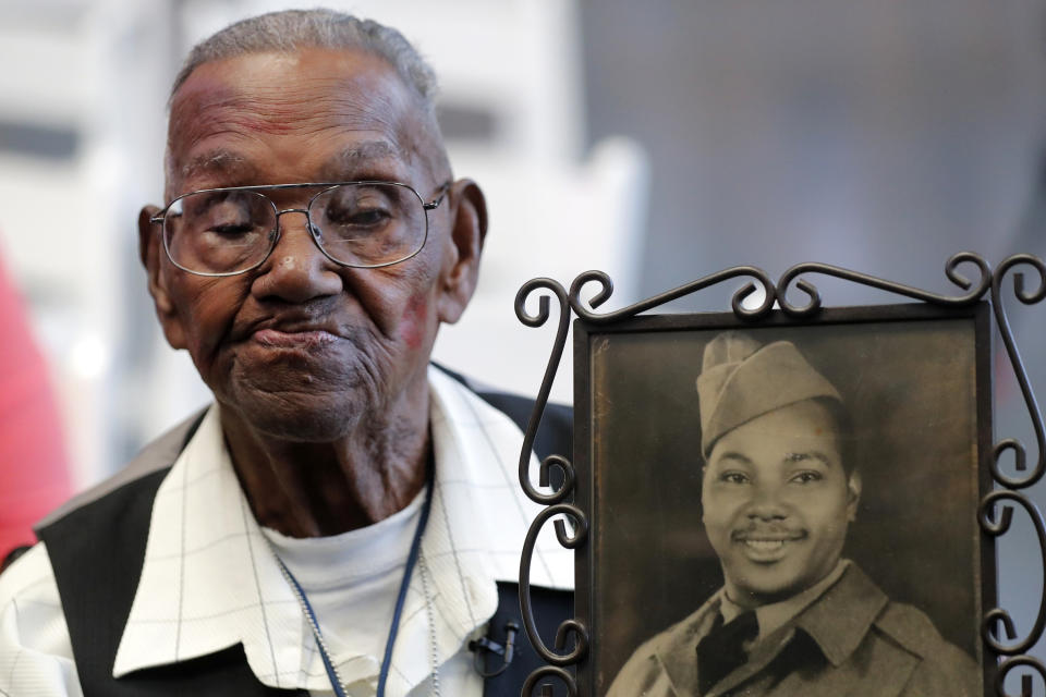 FILE - World War II veteran Lawrence Brooks holds a photo of him taken in 1943, as he celebrates his 110th birthday at the National World War II Museum in New Orleans, on Sept. 12, 2019. For Veterans Day, a group of Democratic lawmakers is reviving an effort to pay the families of Black servicemen who fought on behalf of the nation during World War II for benefits they were denied or prevented from taking full advantage of when they returned home from war. (AP Photo/Gerald Herbert, File)