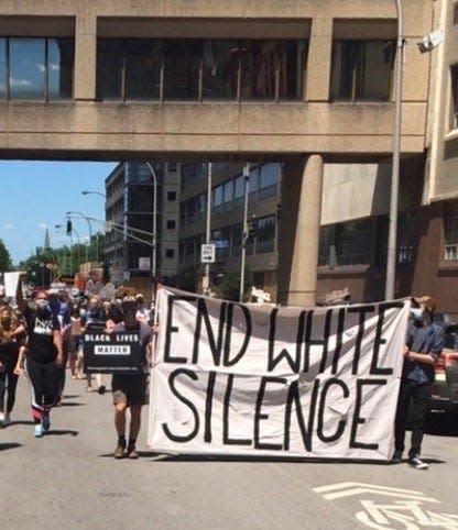 Members of Showing up for Racial Justice carry a banner "End White Silence"