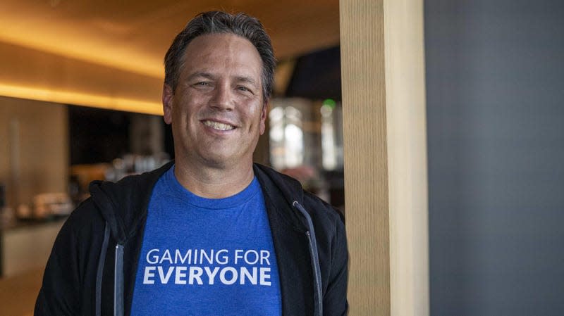 Phil Spencer grins while wearing a blue t-shirt that says 