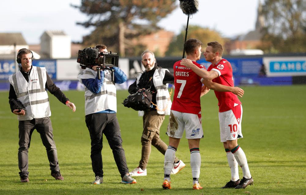 Wrexham players Jordan Davies and Paul Mullin embrace after the final whistle as they are filmed by the Welcome to Wrexham documentary crew