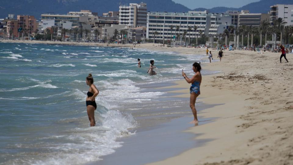 Menschen gehen am Strand von Arenal schwimmen.