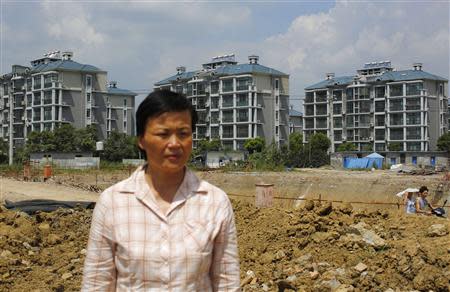 Xu Haifeng poses at a construction site area where her house stood in Wuxi, Jiangsu province, August 20, 2013. REUTERS/Carlos Baria