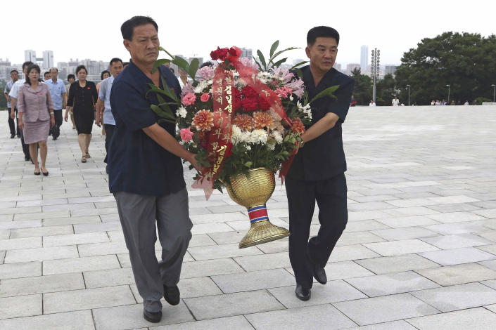 Visitors carry flowers to the statues of President Kim Il Sung and Chairman Kim Jong Il on Mansu Hill to commemorate the 77th anniversary of Korea's Liberation in Pyongyang, North Korea, Monday, Aug. 15, 2022. (AP Photo/Jon Chol Jin)