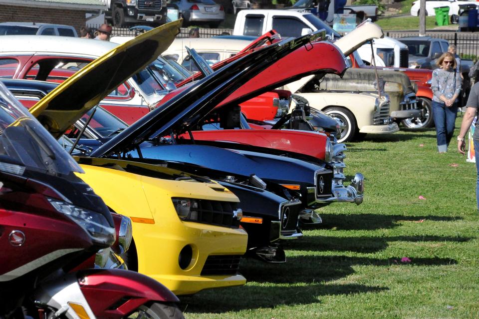 A row of cars with hoods up for inspection in the ribfesrt car show.