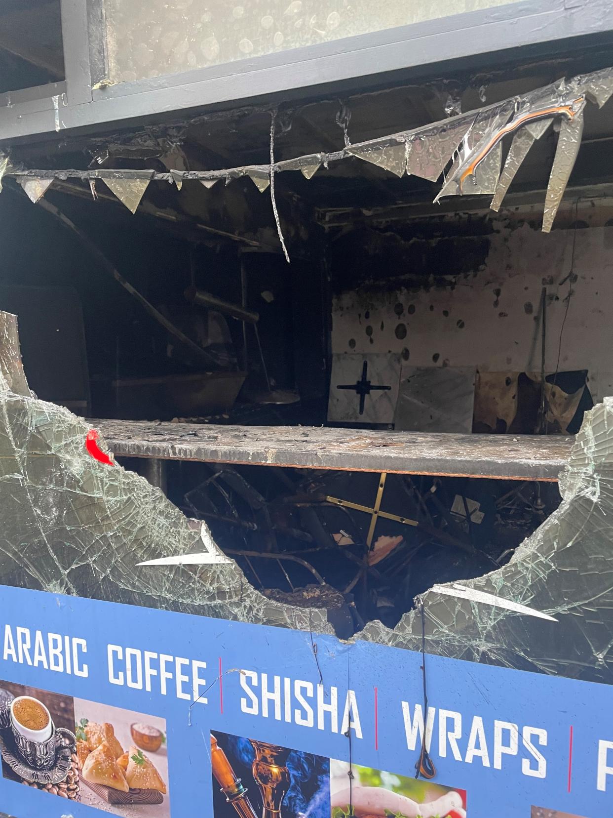 A view through a broken window of the inside of a burnt-out business premises