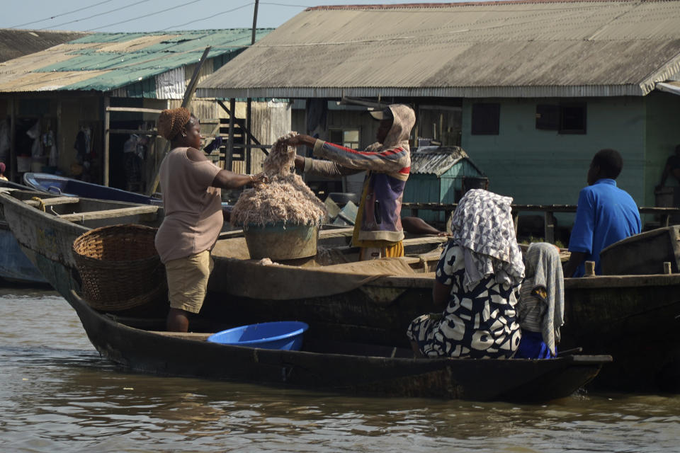 People buy crayfish at the coastal area of Ayetoro, in Southwest Nigeria, Thursday, April 4, 2024. Ayetoro, a coastal community more than 200 km southeast of Nigeria's business capital Lagos, has been experiencing coastal erosion for many years. But the changes have recently rapidly worsened with the community slumping into the Atlantic Ocean, leading to repeated displacements of households and businesses. (AP Photo/Dan Ikpoyi)