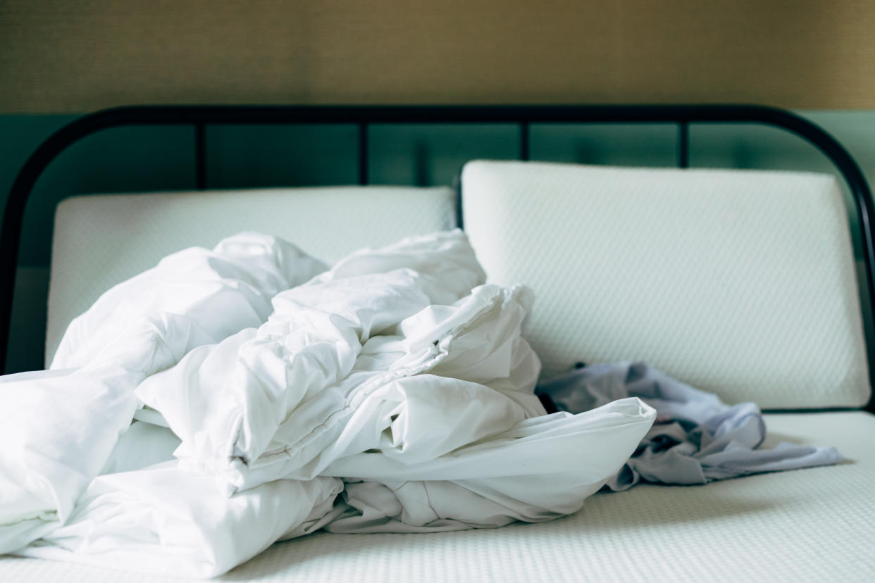 Clean white bedding in a room, on an unmade bed