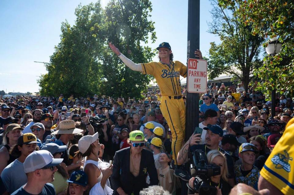 Savanna Bananas’ DR Meadows (5) climbs on a pole over the crowd during the march before the Savannah Bananas World Tour on Saturday, July 29, 2023, at Sutter Health Park in West Sacramento.