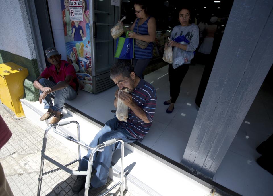 En esta imagen, tomada el 20 de marzo de 2017, un hombre come pan tras comprarlo en una panadería privada en Caracas, Venezuela. En un intento para controlar la producción de pan subvencionado, el gobierno realiza registros en unas 700 panaderías y las autoridades anunciaron incluso la detención de dos personas por hornear brownies de forma ilegal. (AP Foto/Fernando Llano)