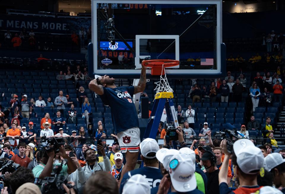 Auburn Tigers guard K.D. Johnson (0) celebrates after cutting his piece of the net after beating Florida in the SEC Men's Basketball Tournament Championship game at Bridgestone Arena in Nashville Sunday.