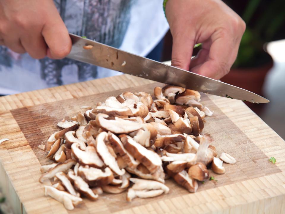 person chopping mushrooms on a cutting board