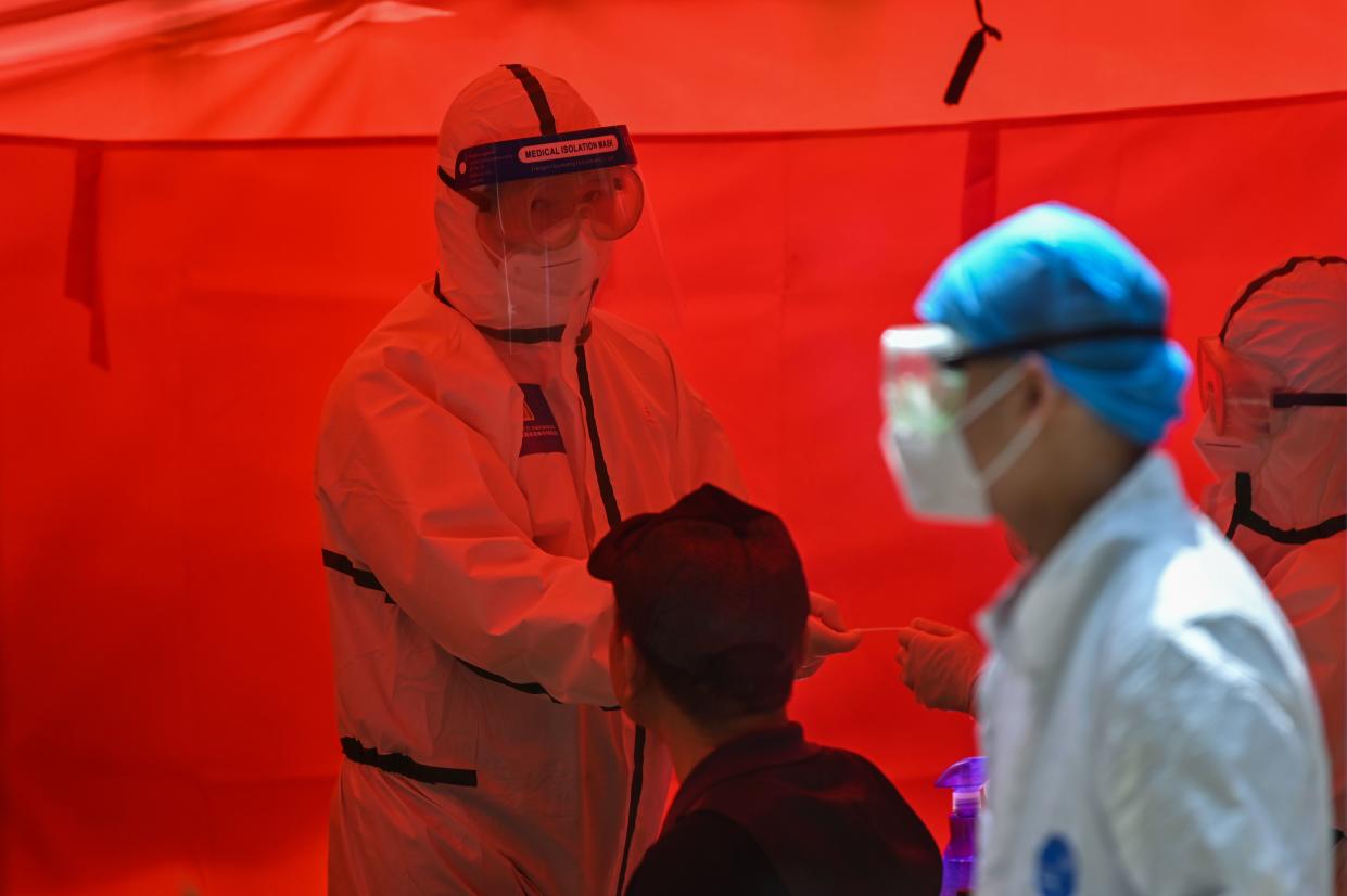 A medical worker prepares to take a swab sample from a man to be tested for the COVID-19 coronavirus in Wuhan, Chinas central Hubei province on May 19, 2020. - Authorities in the pandemic ground zero city of Wuhan have ordered mass COVID-19 testing for all 11 million residents after a new cluster of cases emerged. (Photo by Hector RETAMAL / AFP) (Photo by HECTOR RETAMAL/AFP via Getty Images)