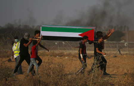 Palestinian demonstrators carry a mock coffin during a protest demanding the right to return to their homeland at the Israel-Gaza border, in the southern Gaza Strip August 3, 2018. REUTERS/Ibraheem Abu Mustafa