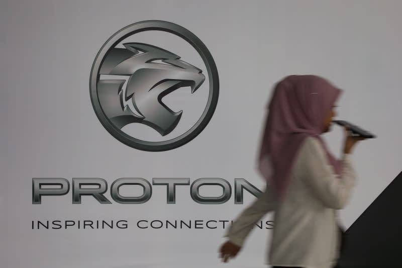 A woman walks past a logo of Proton at its headquarters in Subang Jaya