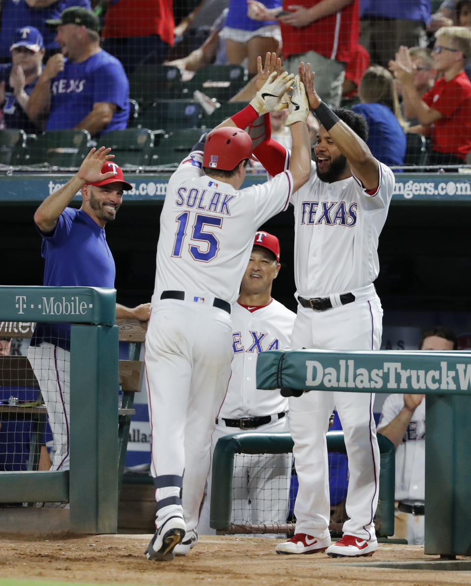 Texas Rangers' Nick Solak (15) is congratulated by manager Chris Woodward, left, and Elvis Andrus, right, after Solak hit his first major league home run in the fifth inning of a baseball game against the Los Angeles Angels in Arlington, Texas, Tuesday, Aug. 20, 2019. The shot came off of Angels starter Jaime Barria. (AP Photo/Tony Gutierrez)