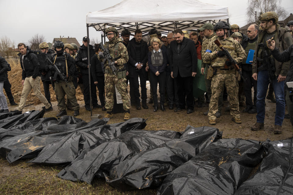 Ursula von der Leyen, European Commission President, center, looks at corpses that were pulled out of a mass grave in Bucha, on the outskirts of Kyiv, Ukraine, Friday, April 8, 2022. (AP Photo/Rodrigo Abd)