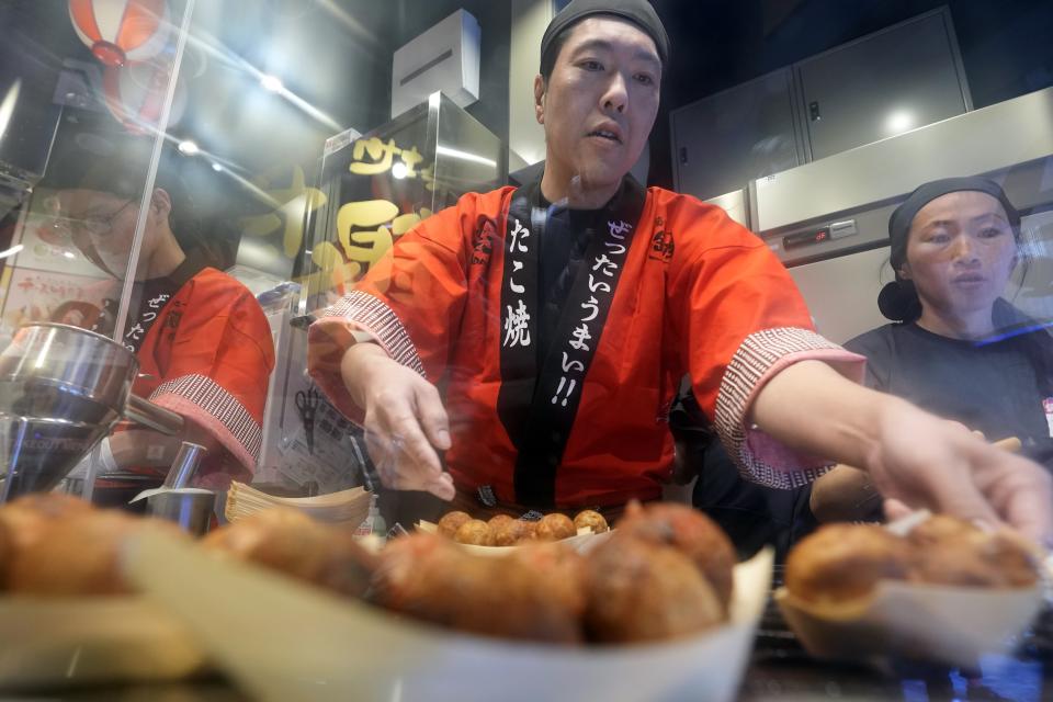 Staff prepare "takoyaki" or octopus dumplings at "Toyosu Senkyaku Banrai," an Edo Period-themed hot spring complex on media preview event at Toyosu Market Monday, Jan. 29, 2024, in Tokyo. Japan's biggest fish market on Thursday opened a long-awaited outer section with Japanese-style seafood restaurants and a spa for relaxation, as the wholesale venue that has struggled since relocating from the beloved Tsukiji market seeks to lure more visitors. (AP Photo/Eugene Hoshiko)