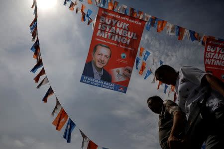 People walk under a pre-election banner depicting Turkish President Tayyip Erdogan in Eminonu district in Istanbul, Turkey, June 21, 2018. REUTERS/Alkis Konstantinidis