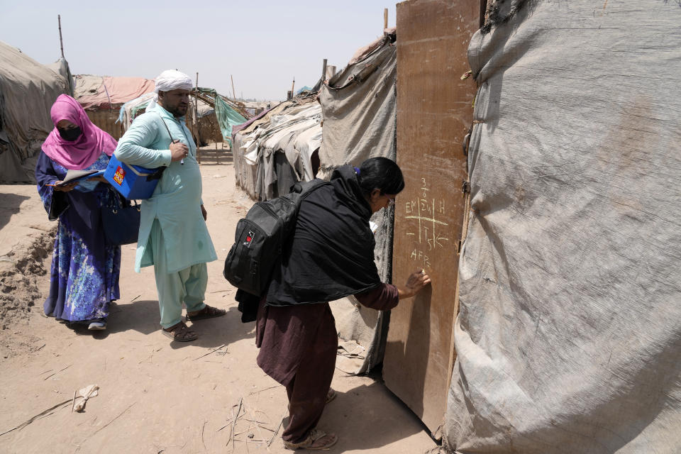 A health worker, right, marks a door of makeshift after administering the polio vaccine to children in a neighborhood of Lahore, Pakistan, Monday, June. 3, 2024. (AP Photo/K.M. Chaudary)