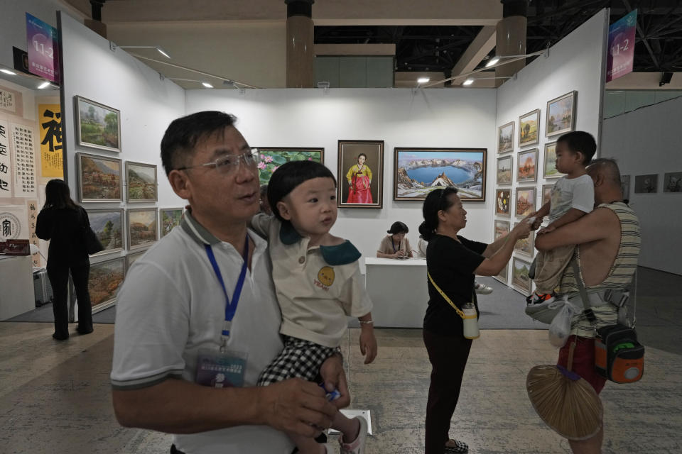 Visitors to the Beijing Art Exposition pass by a booth displaying North Korean paintings run by The Paintings Say Arirang gallery that trumpets itself as China's premier seller of North Korean art, in Beijing Sept. 8, 2023. The gallery's existence and conspicuous sales tactics, experts say, highlight China's lax enforcement of U.N. sanctions targeting North Korea to stymie Pyongyang's nuclear program. (AP Photo/Ng Han Guan)